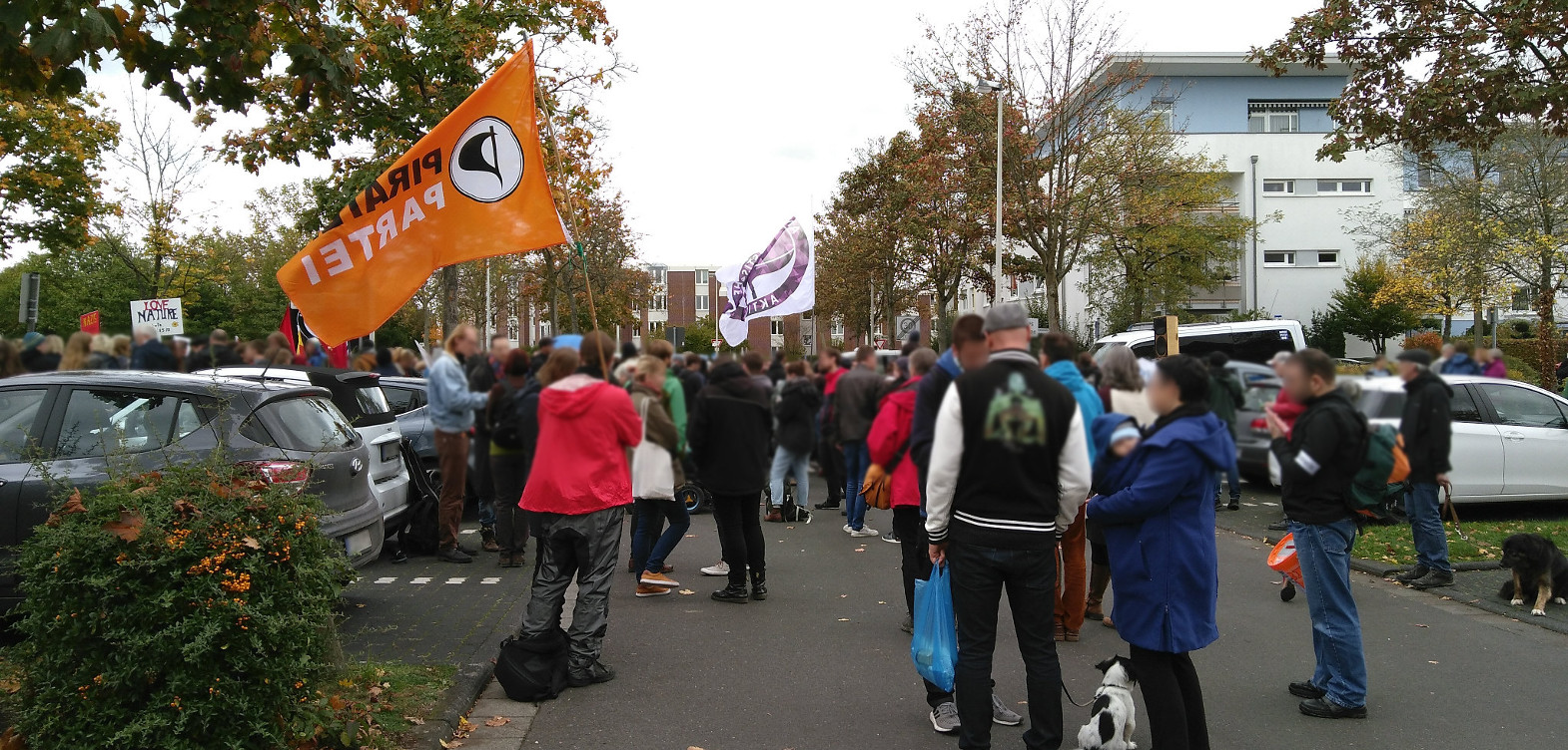 Menschenmasse mit u.a. Piratenparteiflagge vor dem Ortsteilzentrum