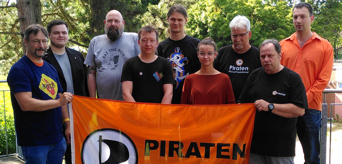 9 Personen draußen. Unten vor ihnen eine Piratenpartei-Flagge