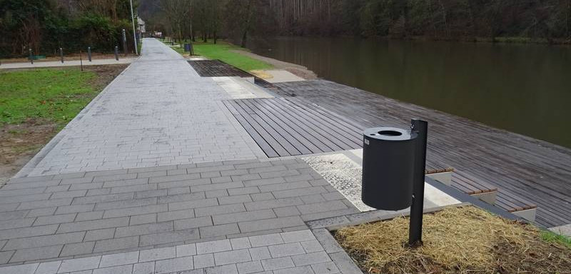 Foto des Siegpromenade. Die Grünflächen werden durch Pflastersteinstrecken unterbrochen und zum Ufer hin sind Holzplanken angebracht