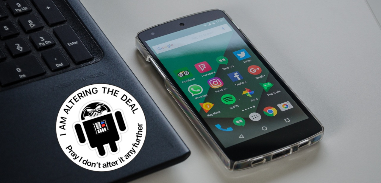 Smartphone auf einem Tisch neben einem Laptop. Auf dem Laptop ist ein Aufkleber "I am altering the deal – Pray I don't alter it any further"