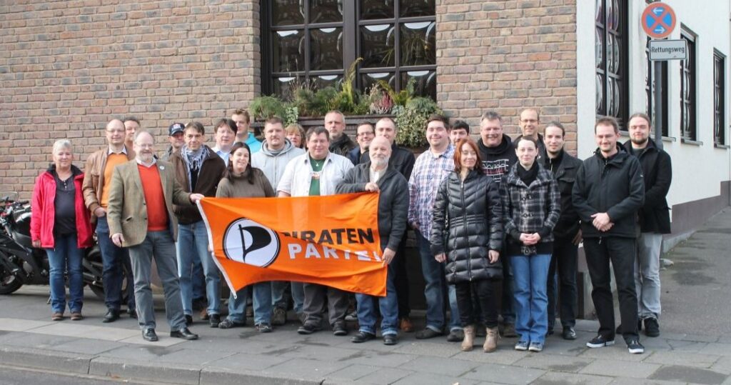 Die Rhein-Sieg-Direktkandidaten draußen vor einem mit einer Piratenpartei-Fahne vor sich gehalten