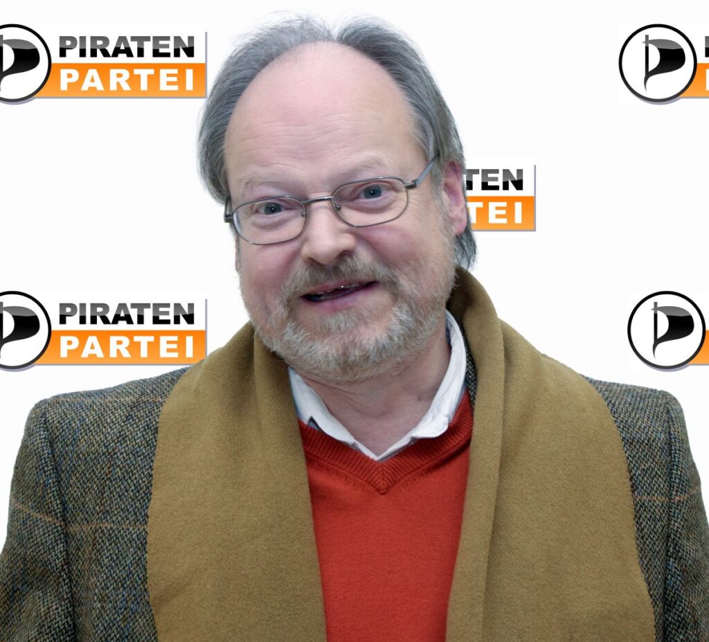 Wolf Roth im Portrait vor einem weißen Hintergrund mit Piratenpartei-Logos